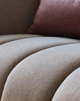 Close-up of a ribbed sofa and a plum cushion. Soft neutral tones and textures create a cosy, contemporary look.