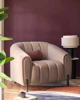 A contemporary neutral armchair with a brown cushion sits on a colourful rug, next to a lamp and a houseplant.
