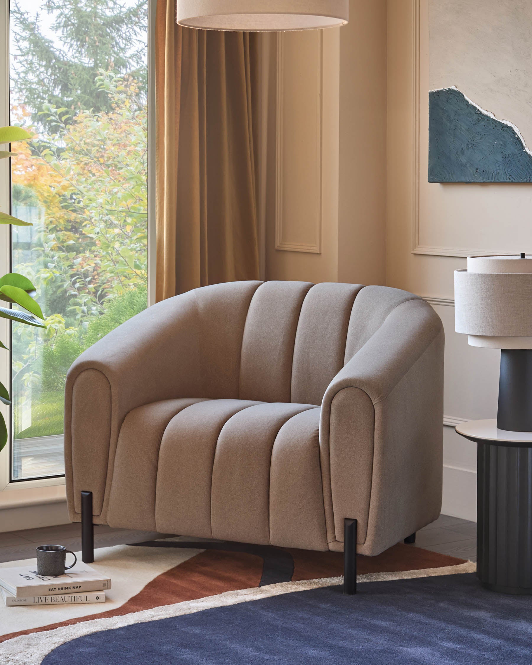 Stylish armchair in a neutral tone, positioned on a rug. Features modern design and complements the lamp table.