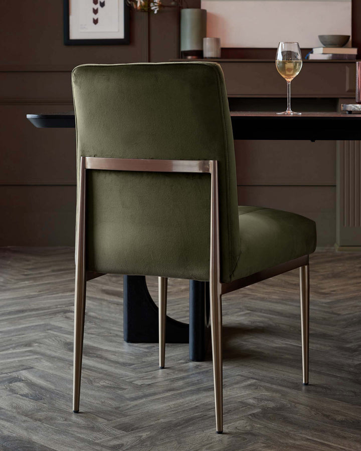 An elegant olive green dining chair with sleek, bronze-coloured metal frame, sits at a table setting with a wine glass.