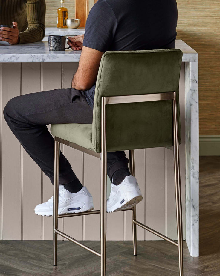 Olive green velvet bar stool with metallic legs and a marble countertop create a stylish, modern aesthetic.