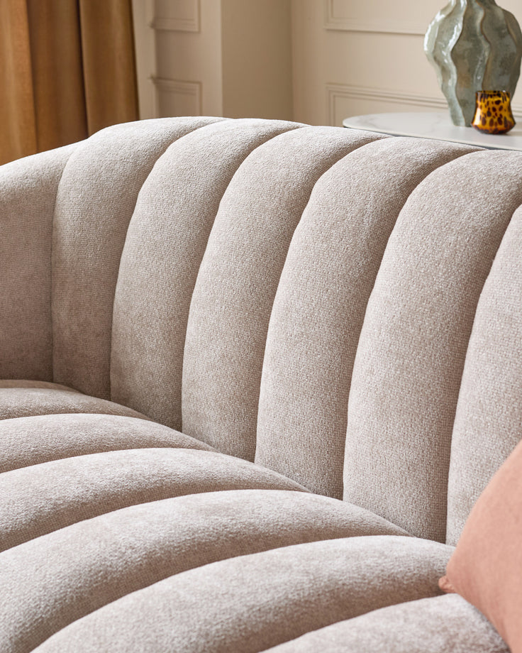 Kendra 3-seater sofa in natural fabric, close-up of curved channel-tufted backrest and seat cushions.