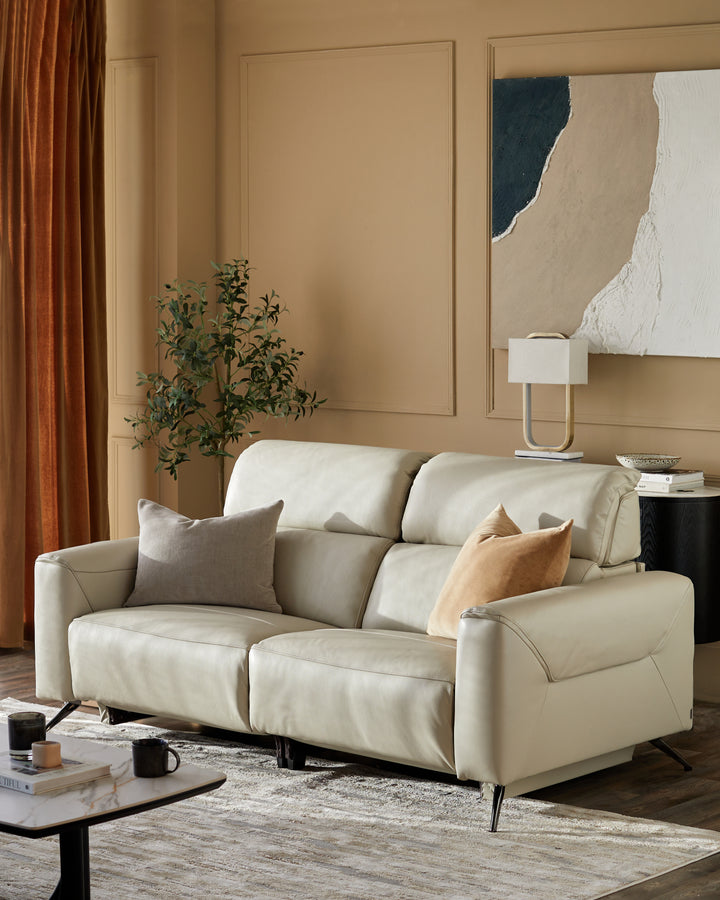 A stylish cream leather sofa with accent cushions, coffee table, lamp and side table set in a warm, inviting room.