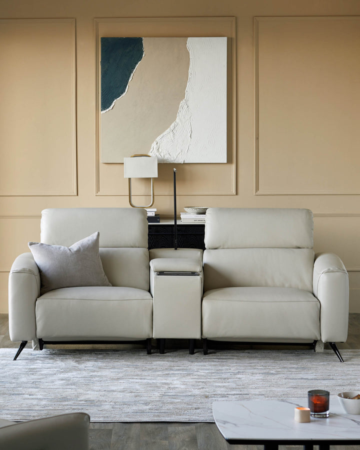 A stylish, contemporary light-cream sofa with a centre console and dark, angled legs sits on a patterned rug.