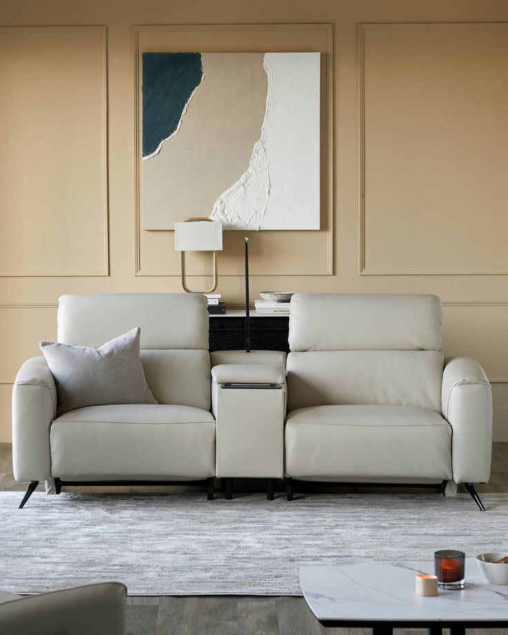 A stylish, contemporary light-cream sofa with a centre console and dark, angled legs sits on a patterned rug.