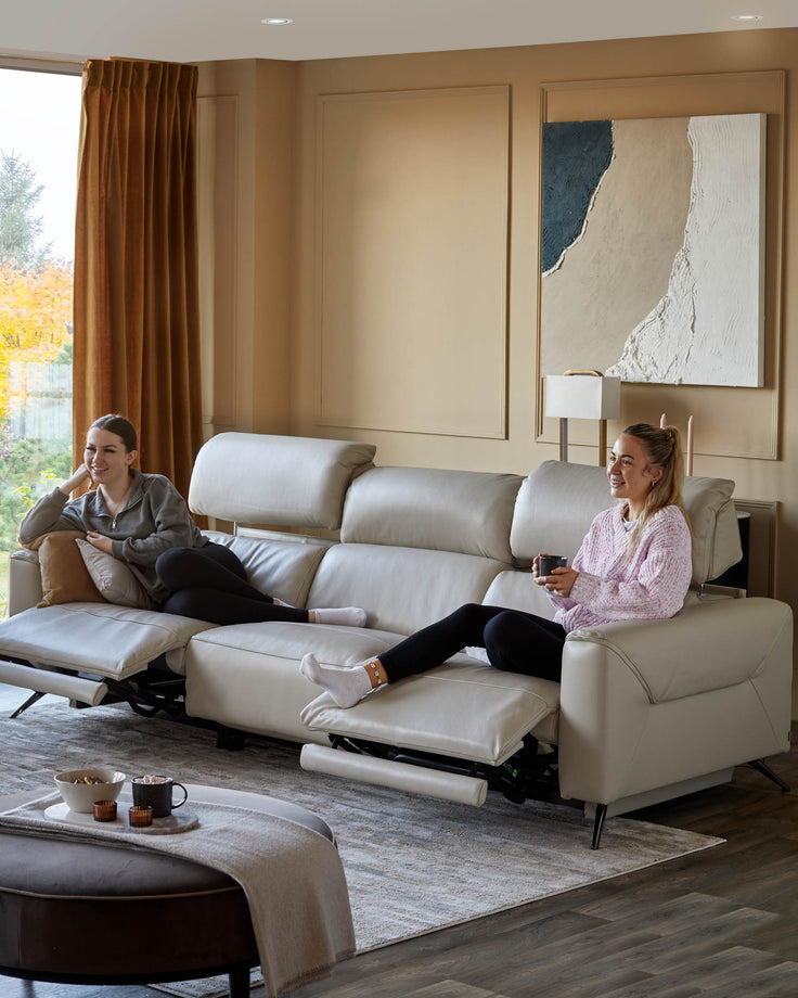 A stylish, reclining leather sofa takes centre stage in this modern living room setting, alongside a dark brown ottoman.