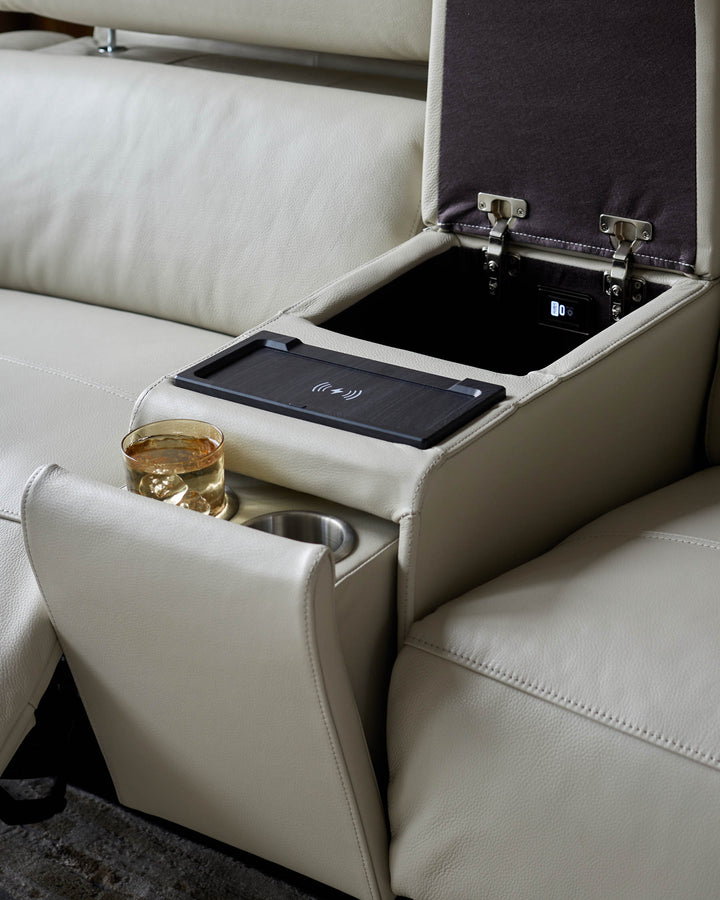 Close-up of a leather sofa with a central console, including a wireless charger, cup holders, and a storage compartment.