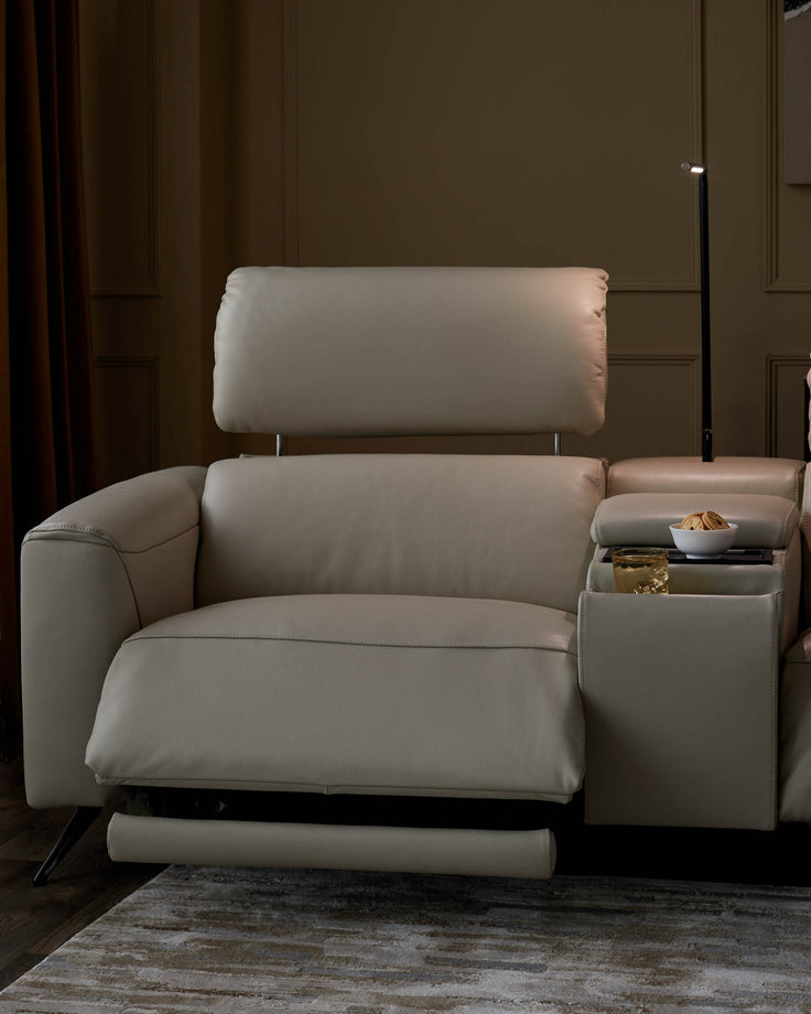 Close-up of a beige leather recliner sofa with a tray table holding a bowl of biscuits and a glass of liquid.