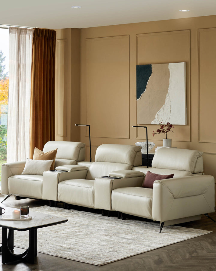 A cream leather three-seater sofa with black side tables and lamps sits on a patterned rug. Neutral tones throughout.