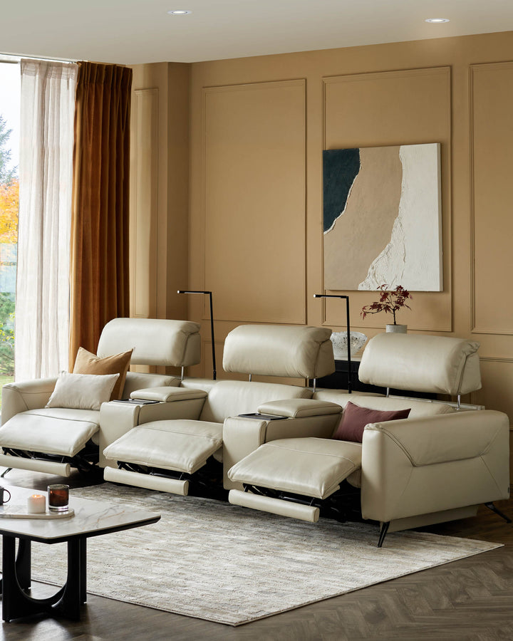 A plush, cream-coloured leather recliner sofa with cup holders and adjustable headrests sits on a neutral rug in a modern living room.