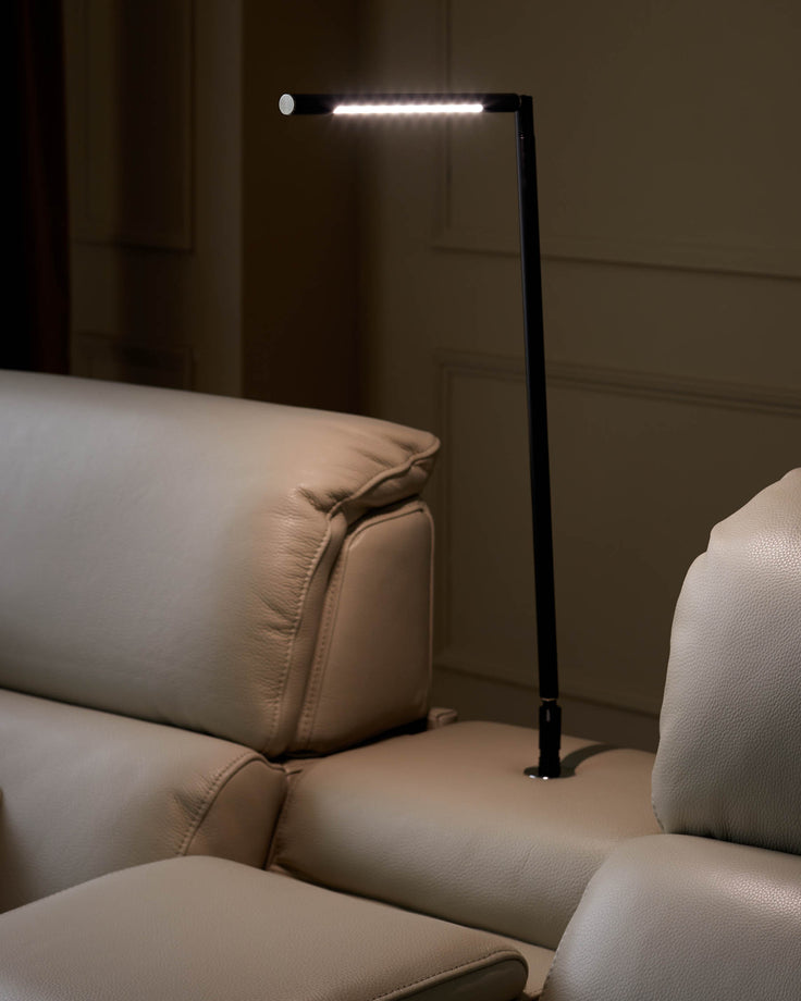 Beige leather sofa with integrated black floor lamp, casting a soft light. Modern design for living rooms.