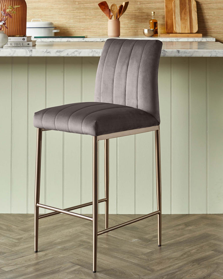 Elegant modern bar stool with a tall, channel-tufted backrest and plush seat in a soft grey velvet fabric, supported by slender bronze-toned metal legs that include a footrest for added comfort.