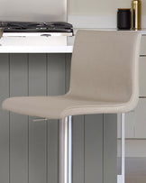 Light grey real leather gas lift bar stool with curved backrest and polished chrome base, shown in kitchen setting.