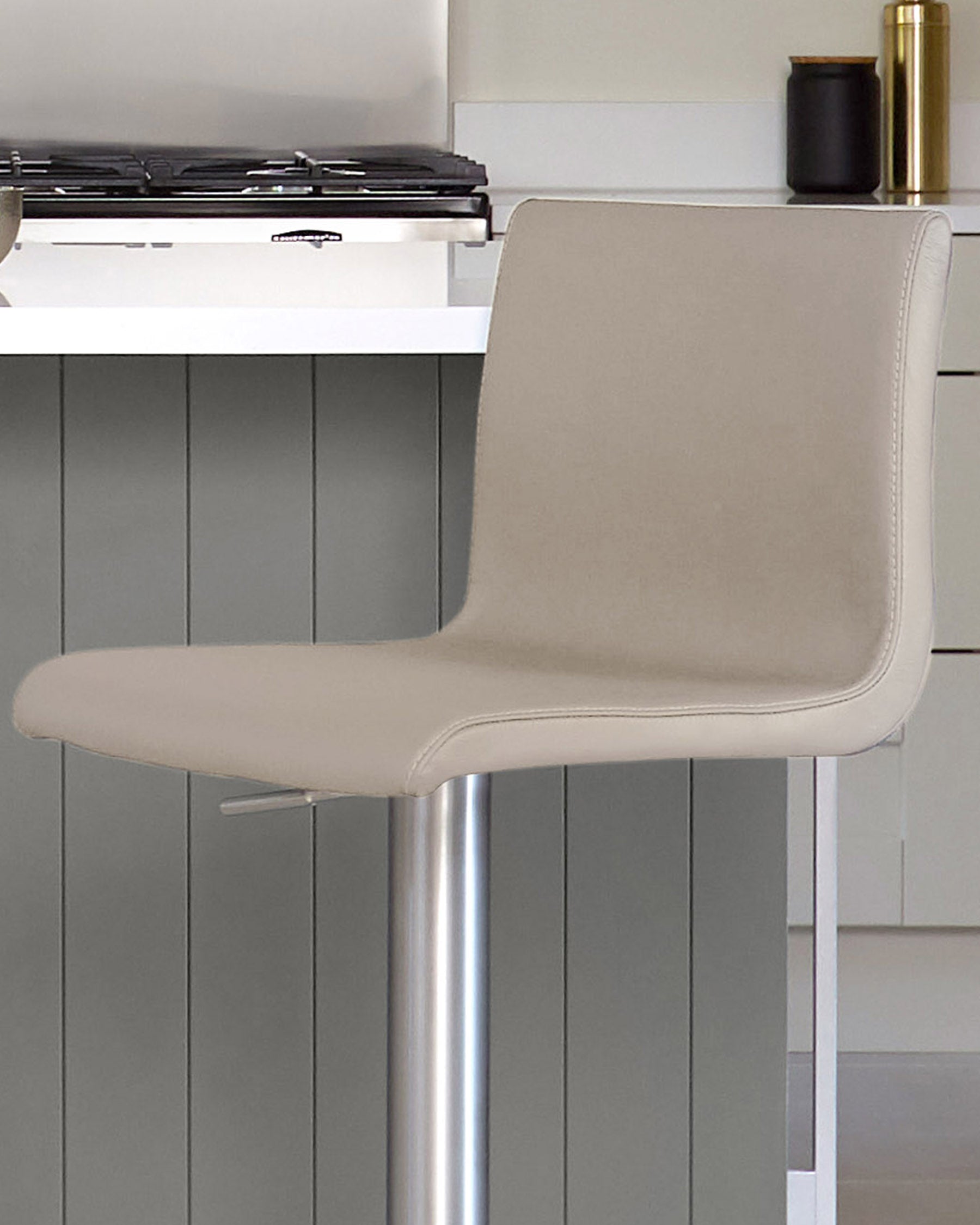 Light grey real leather gas lift bar stool with curved backrest and polished chrome base, shown in kitchen setting.