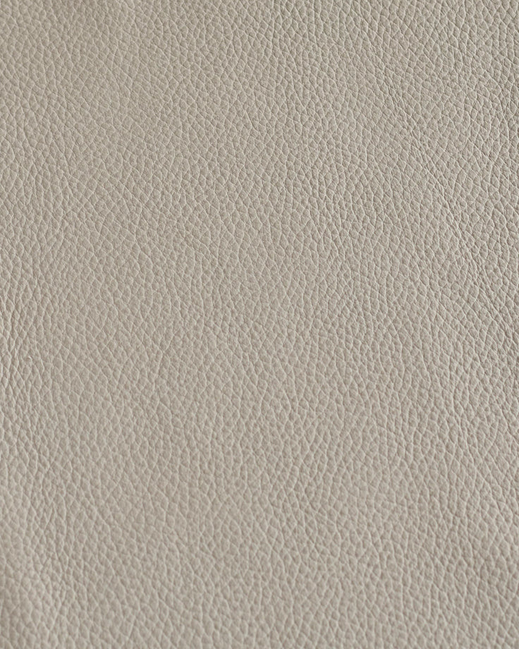 Close-up of light grey leather. Neutral tone, fine grain, classic texture, ideal for high-end upholstery, furniture and design.