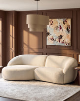 Kimberley left-hand chaise 3-seater sofa in natural fabric with curved, rounded design in warm cream living room setting.