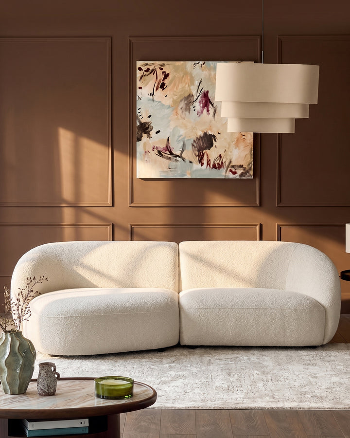 Kimberley left-hand chaise 3-seater sofa in natural fabric, curved design, displayed in warm brown living room setting.