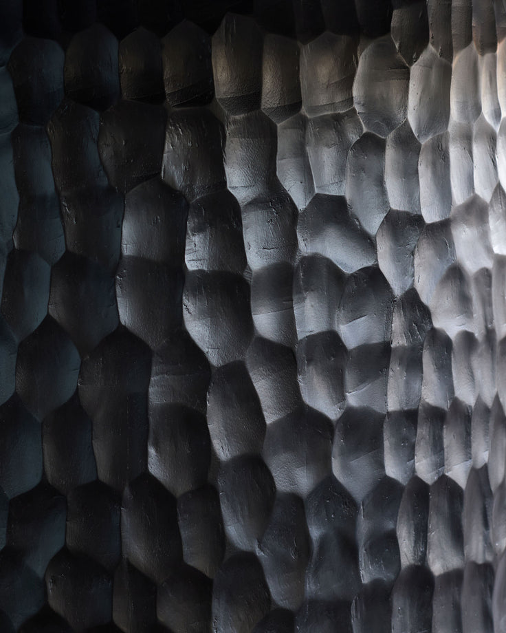 Close-up of black wood texture showing scaled surface detail on Knox dining table