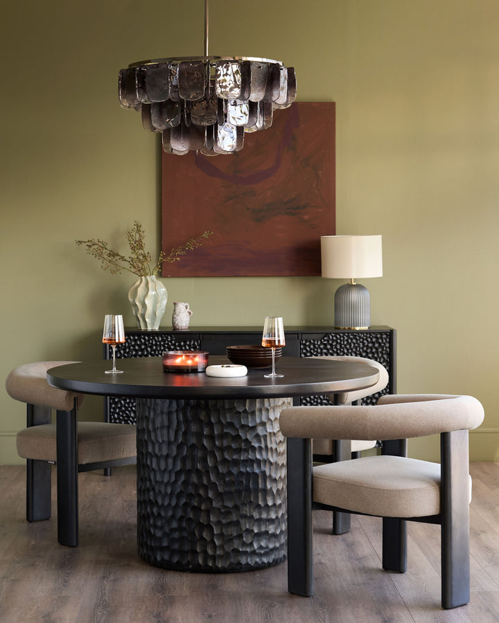 Knox 6-seater round dining table in black wood with textured cylindrical base, styled with beige chairs.