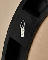 Black round mirror with silver handle and mounting hardware, angled detail view.