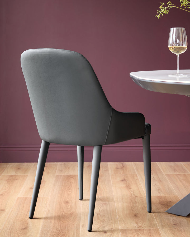 Dark grey faux leather dining chair with curved backrest and tapered black legs, shown from rear angle.