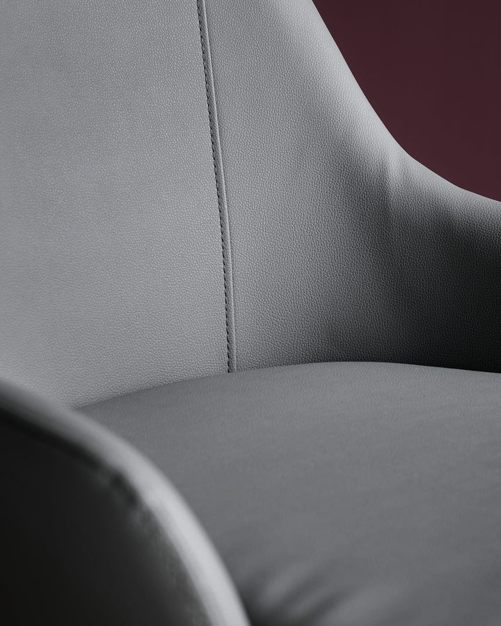 Kyro faux-leather dining chair in dark grey, close-up showing textured upholstery and stitched seam detail.