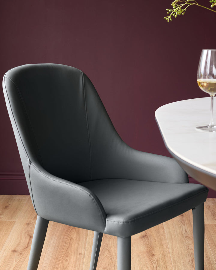 Dark grey faux leather dining chair with curved backrest and black legs, shown at a round white table with wine glass.