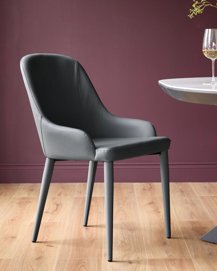 Dark grey faux leather dining chair with curved backrest and tapered legs, styled in modern interior setting.