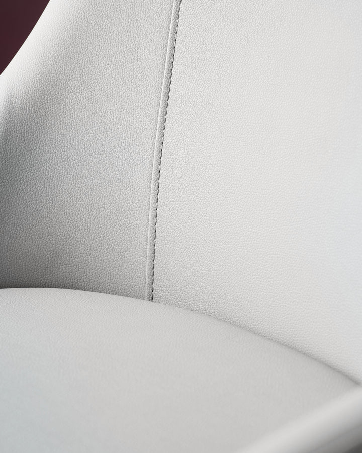 Kyro faux-leather dining chair in light grey, showing close-up detail of the seat and backrest seam.