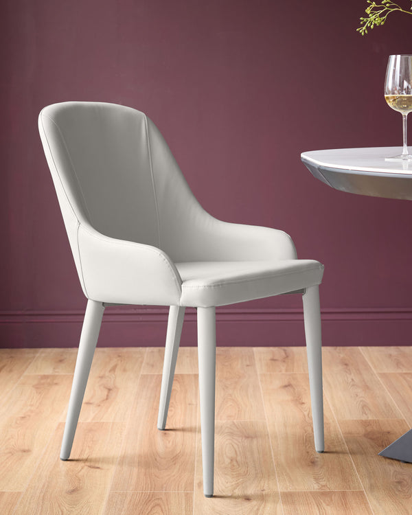 Light grey faux leather dining chair with curved backrest and tapered legs, shown in an elegant room setting.