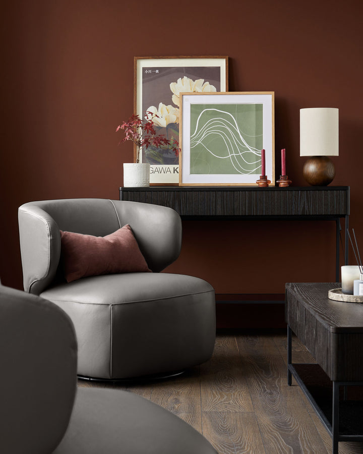 Stylish living room furniture: grey swivel chairs, dark wood console and coffee table. Lamps, artwork and candles complete the look.
