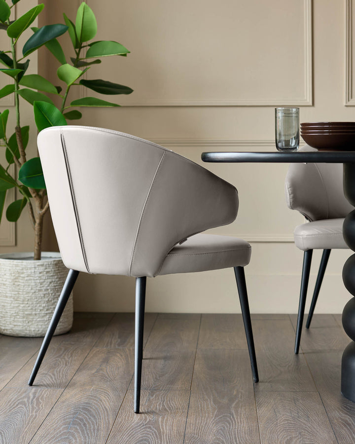 Light grey leather dining chair with curved back, black metal legs, displayed in modern dining room setting.