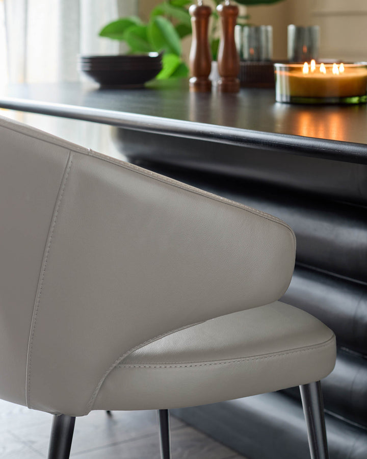 Landon light grey real leather dining chair, side view showing curved backrest and metal legs at a kitchen counter.