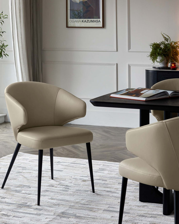 Elegant beige chairs with black legs beside a sleek black table, complemented by a soft area rug and contemporary decor.