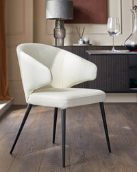 A cream leather dining chair with black metal legs sits in front of a dark wood sideboard.