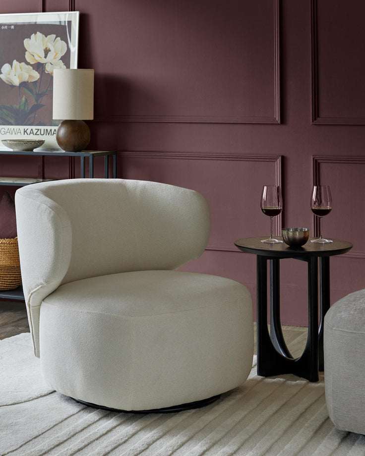 Stylish cream armchair and dark wood side table with wine glasses, adding a touch of luxury to any living space.