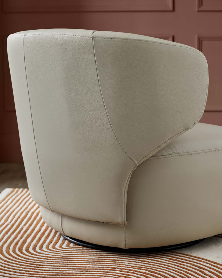 Contemporary swivel armchair in pale grey leather. Upholstered chair with rounded back and sleek design.