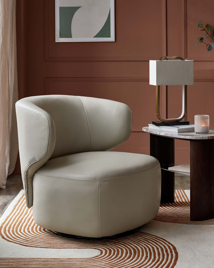 Stylish swivel chair beside a lamp table with marble top and geometric rug, creating a cosy, modern living space.