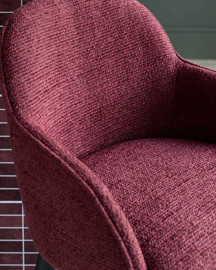 Close-up of a stylish, crimson upholstered chair with a textured fabric finish, exuding comfort and modern design.