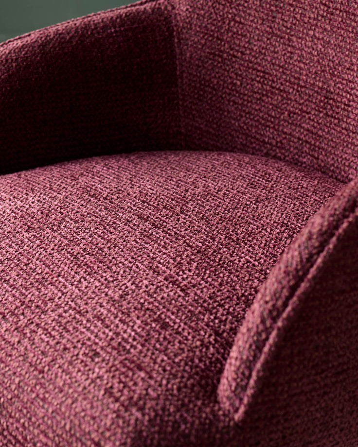 Close-up of a plush, textured armchair in a deep burgundy colour. Comfortable and stylish seating.