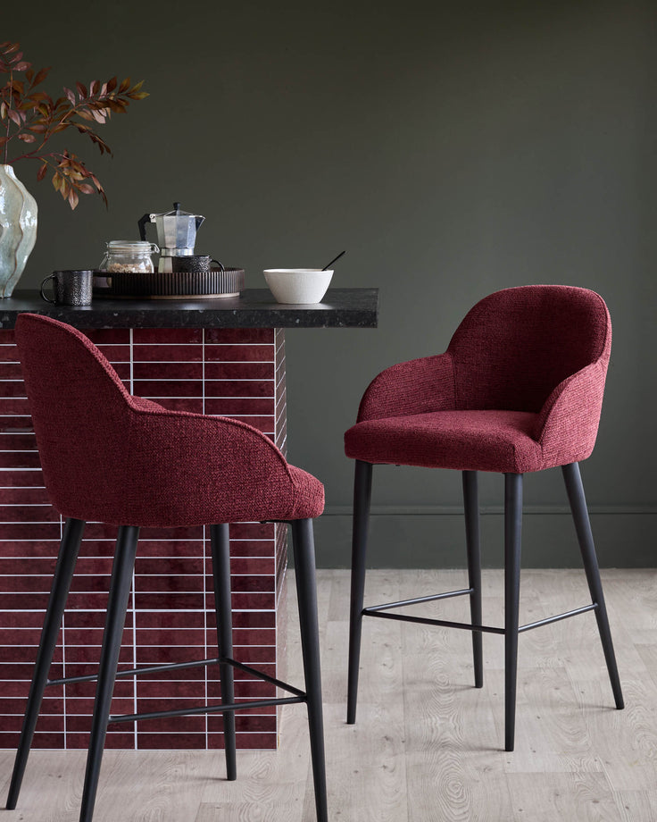 Two red bar stools with black legs sit beside a tiled kitchen island, offering stylish and comfortable seating.