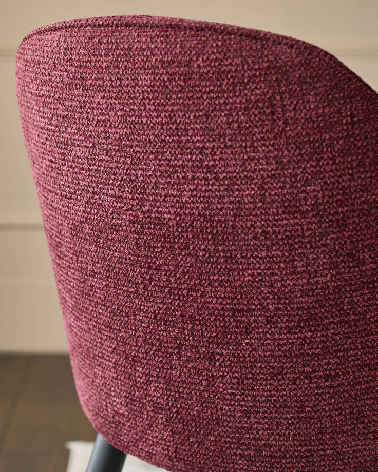 Close-up of a stylish, upholstered chair in a rich, textured fabric. Modern design with a comfortable curve.