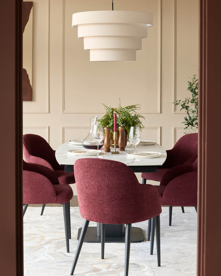 A modern dining set with a marble-effect table, burgundy chairs and a tiered lamp. A stylish and inviting dining space.