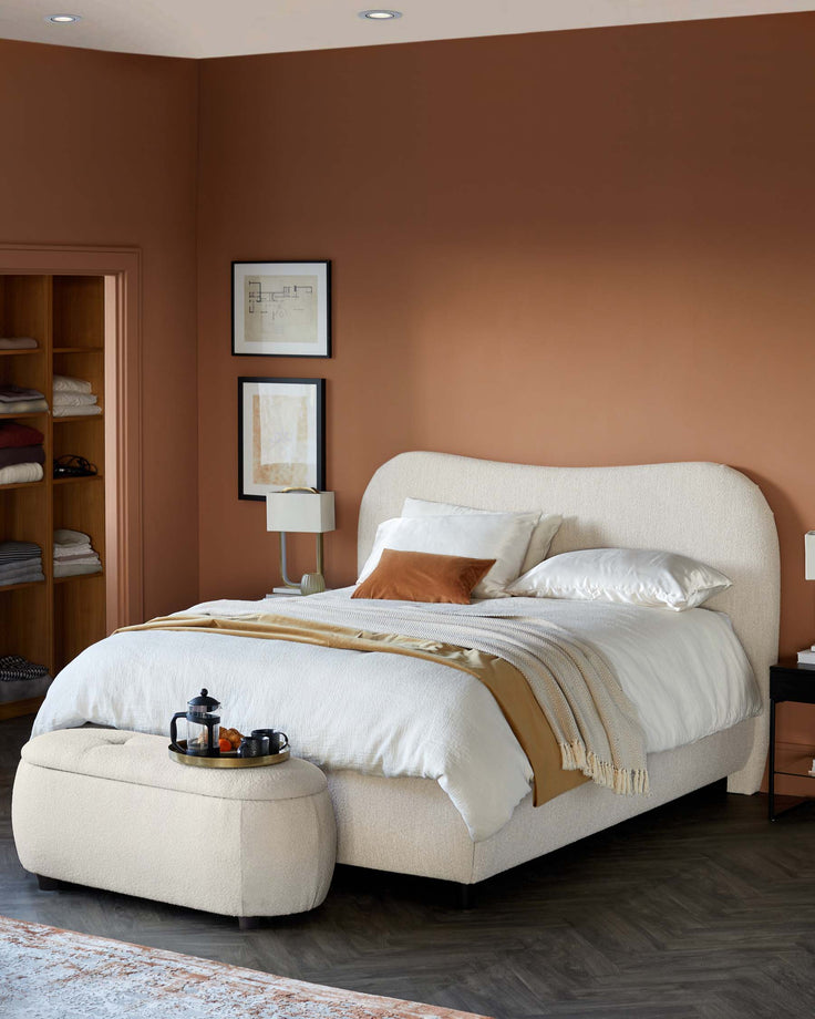 Cozy bedroom featuring a soft upholstered bed, stylish ottoman, elegant side table, and warm earthy wall tones.