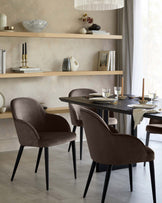 Mocha velvet dining chair with curved backrest and black tapered legs, shown in dining room setting.