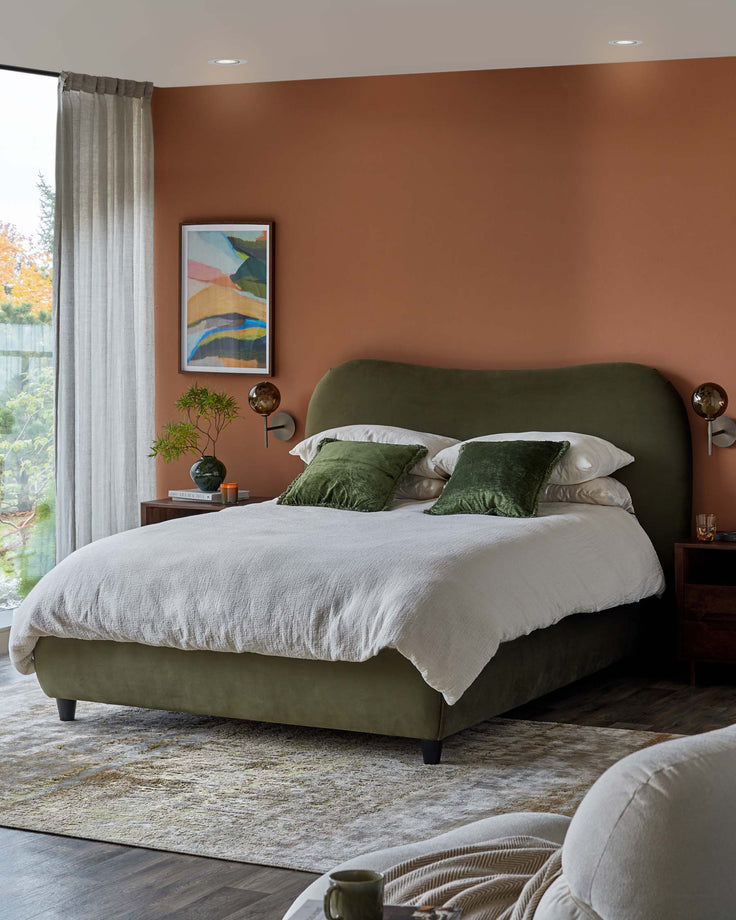 A stylish bedroom featuring an olive green upholstered bed, wooden bedside tables, and abstract wall art.