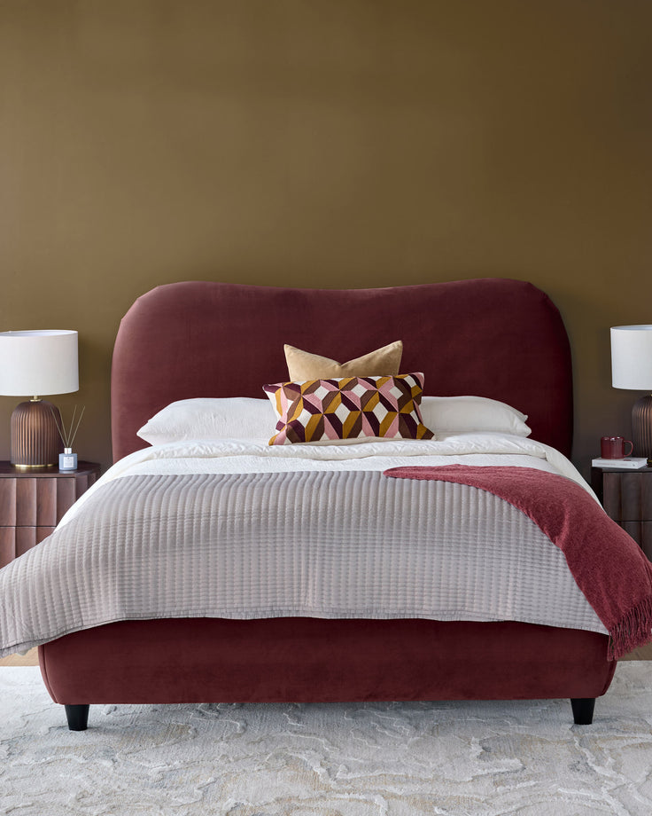 Lani King Ottoman Bed in plum velvet with curved headboard, styled with white bedding and decorative pillows.