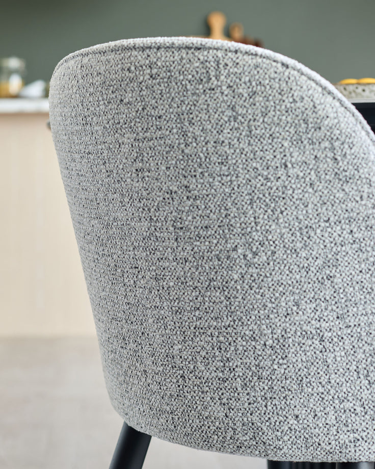 Close-up of a textured grey upholstered chair with black legs, adding modern style to any dining area.