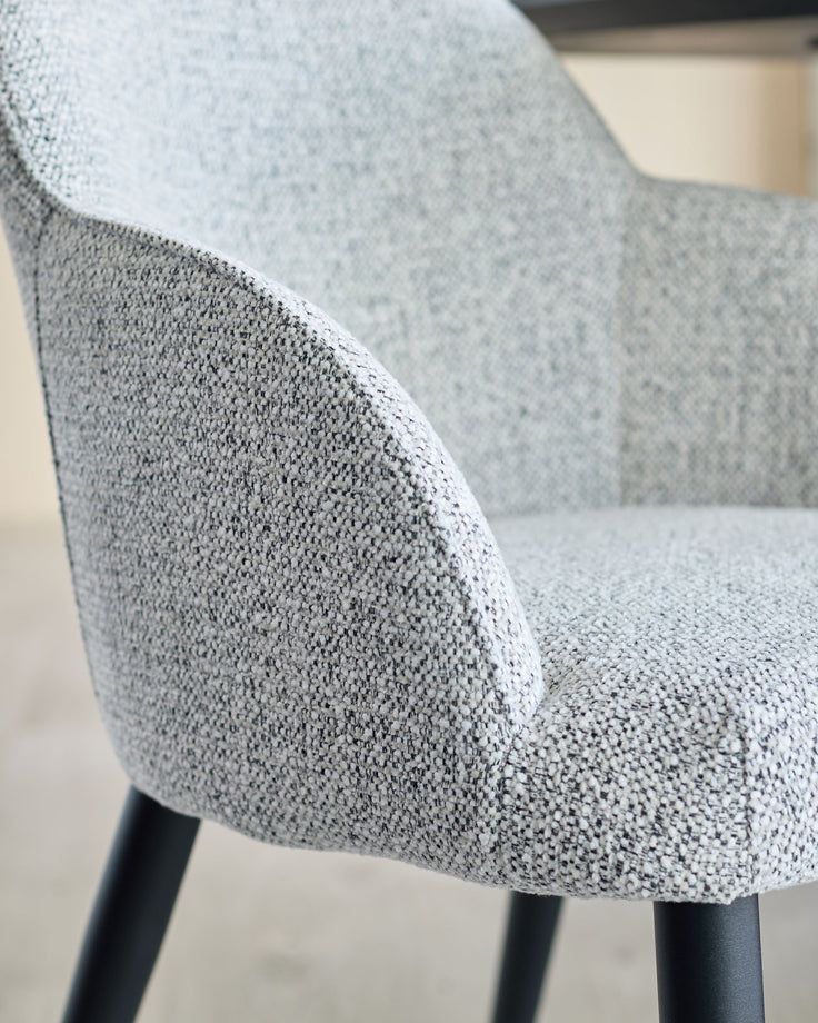 Close-up of a stylish grey upholstered chair with black legs, showcasing the fabric texture and modern design.
