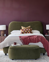 Olive green bed with matching ottoman and bedside tables. Features a plum-coloured feature wall.